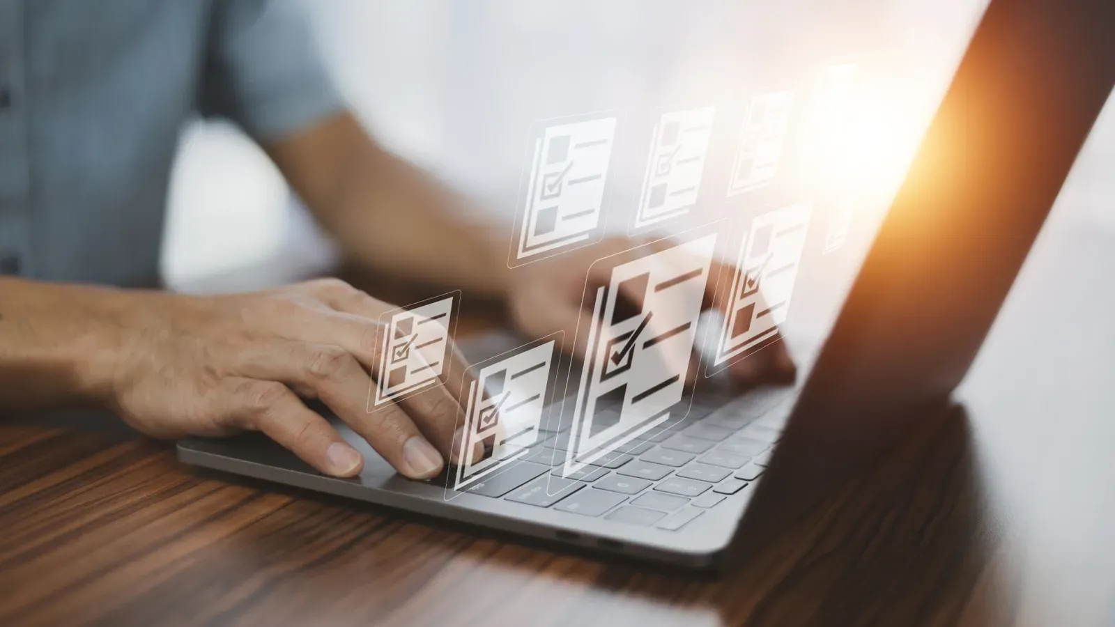 Mani su una tastiera di laptop, con moduli e caselle di spunta che si sollevano dallo schermo